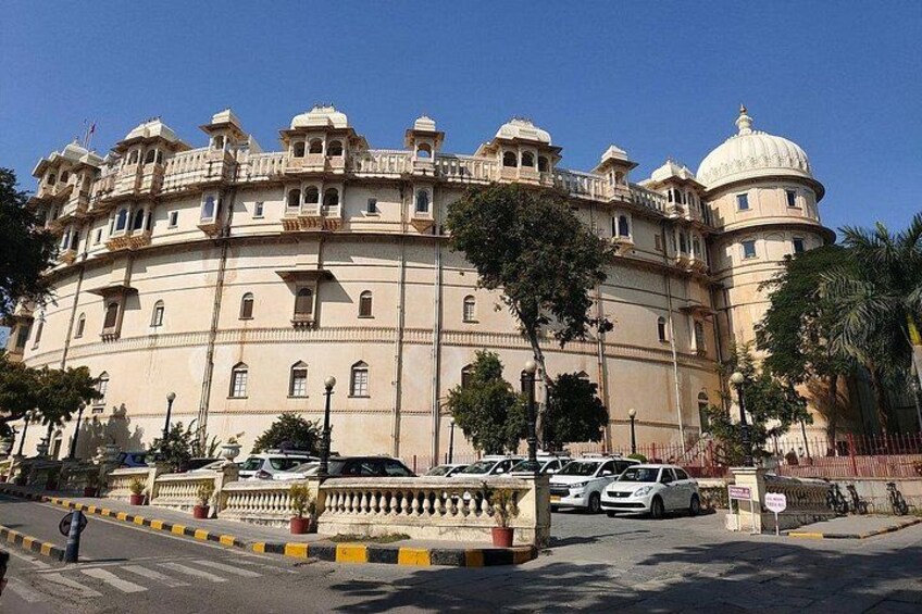 A large, historic building with multiple domes and balconies, surrounded by trees and a street with parked cars. 5