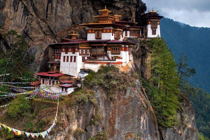 A monastery perched on a cliffside with traditional architecture, surrounded by lush greenery and mountains. 1