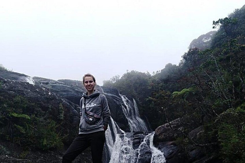 Une personne se tient près d’une cascade dans une zone boisée. 4