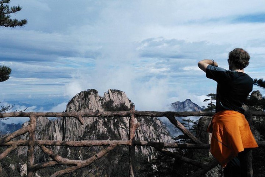 Una persona de pie junto a una cerca de madera, contemplando un paisaje montañoso. 2