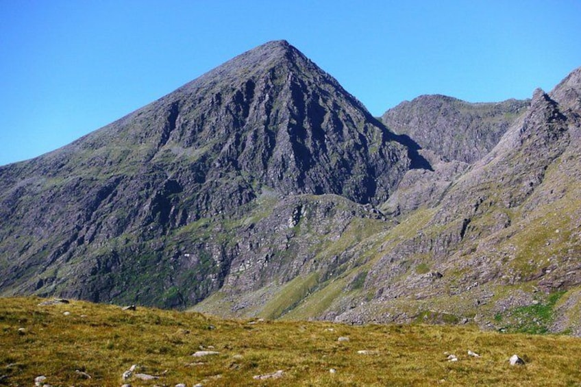 Una montaña con un primer plano herboso y terreno rocoso. 4