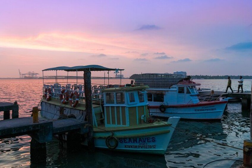 A sunset at a harbor with two boats docked, one labeled 'SEAWAVES' and another with a red and white hull. 1