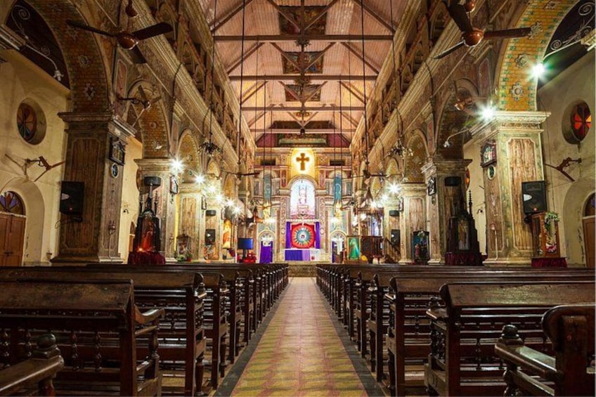 An interior of a church with rows of pews, a central altar, and religious statues. 2