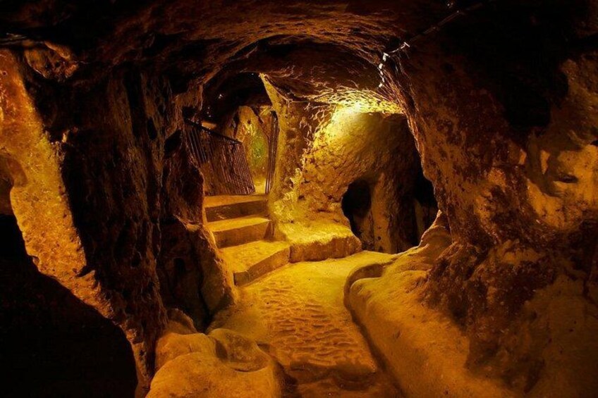 Une grotte faiblement éclairée, avec un escalier menant à un niveau supérieur. 4