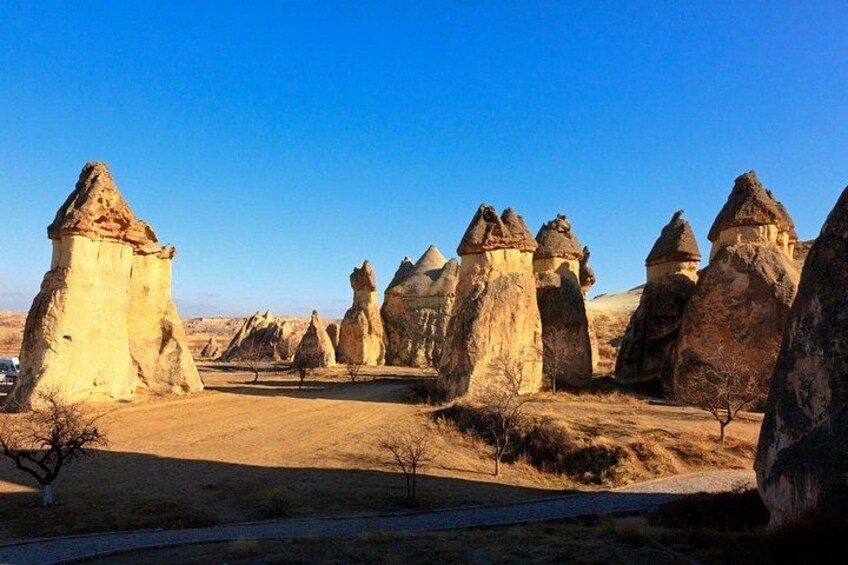 Un paysage caractérisé par des formations rocheuses imposantes, un ciel dégagé et un sentier de terre. 5