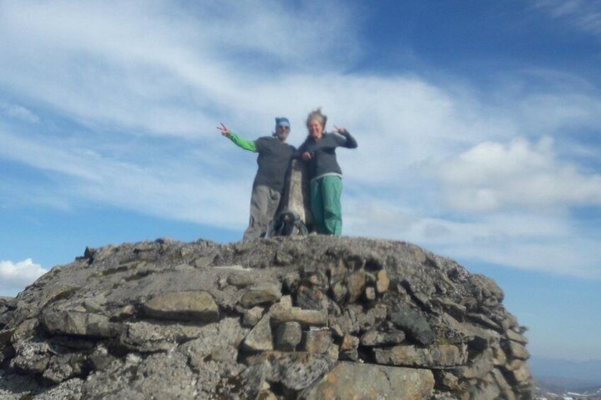 Two people standing on a rocky hilltop with a clear sky. 2