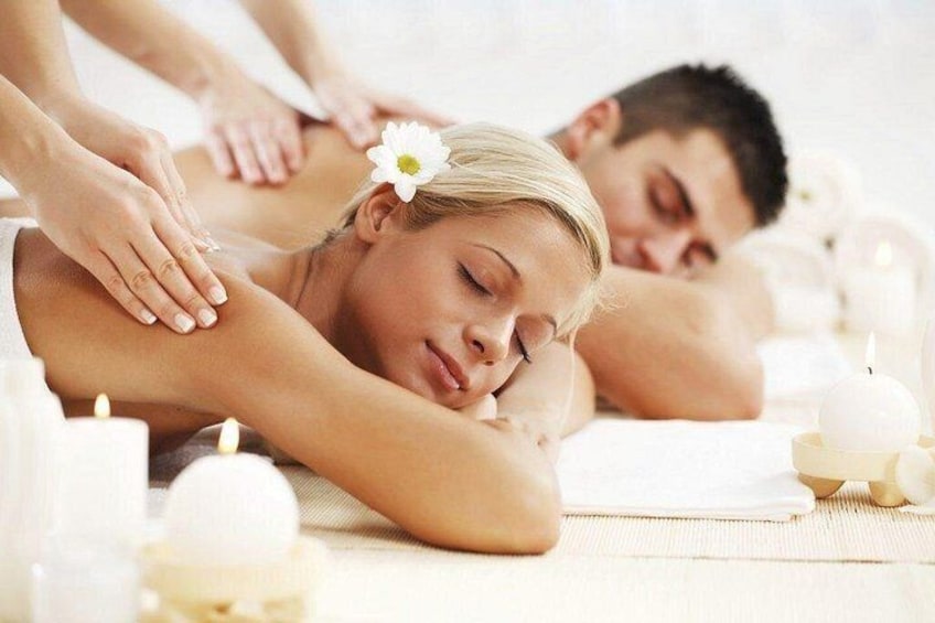 A spa setting with a massage table, candles, and a person receiving a massage. 1