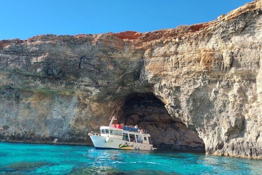 A boat near a rocky cliff with a cave entrance. 2
