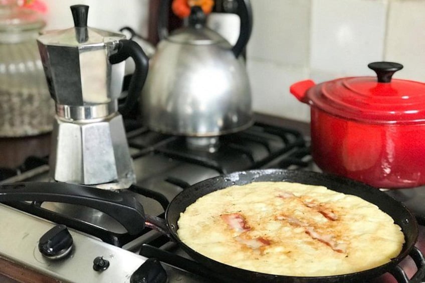 A stove with a frying pan on it, a red pot, and a coffee maker. 5