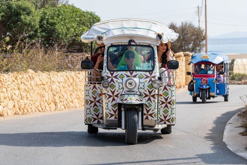 A colorful, patterned vehicle with passengers on a road. 1