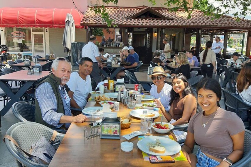 A group of people dining at an outdoor restaurant with tables and chairs. 5