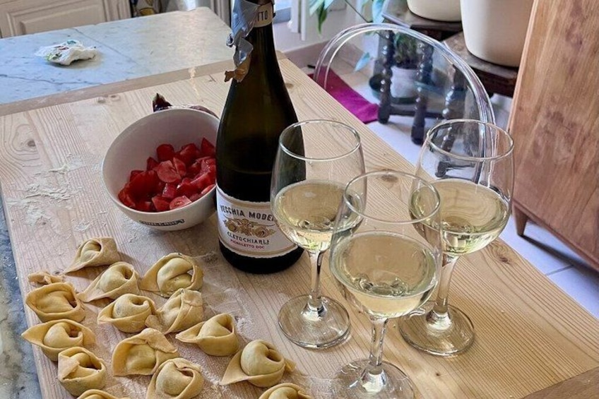 Une planche à découper en bois, des pâtes, une bouteille de vin blanc et des verres. 4