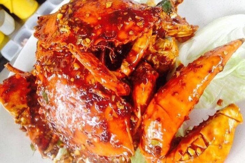 A cooked crab with a glossy, reddish-brown sauce, garnished with herbs, served on a white plate with lettuce. 4