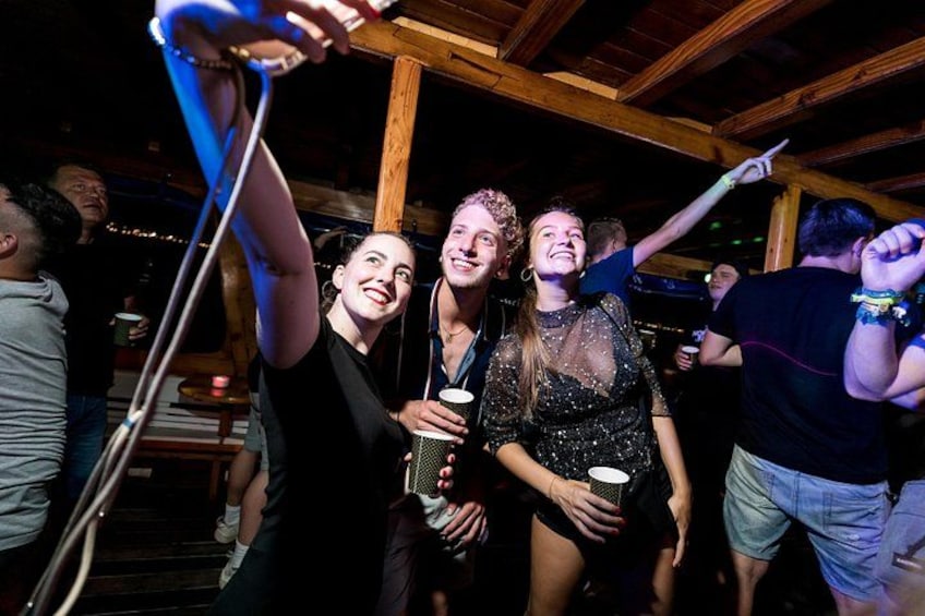 Menschen in einer Holzhütte, möglicherweise eine Bar oder ein Club, wobei eine Person ein Getränk hält. 3