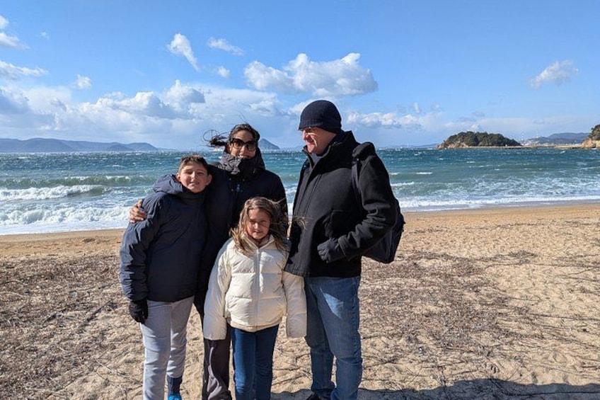 A family of four on a beach with the ocean and distant mountains in the background. 4