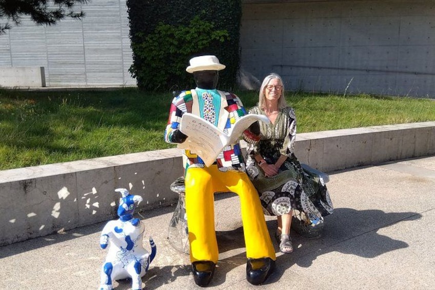 A person sitting on a yellow bench with a colorful sculpture nearby. 5