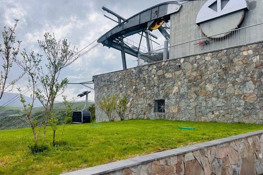 Un edificio moderno con fachada de piedra, estructura metálica en el techo y un área verde con árboles. 2