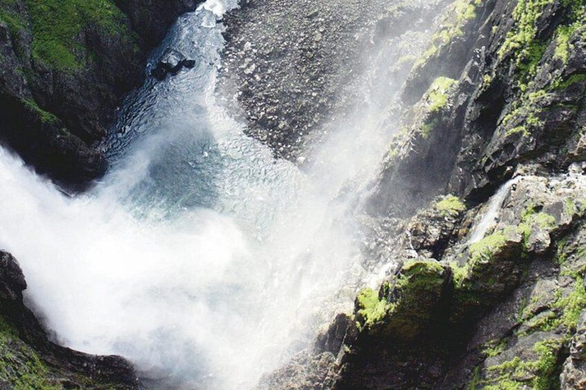 A waterfall cascading down a rocky cliff with moss-covered surfaces. 4