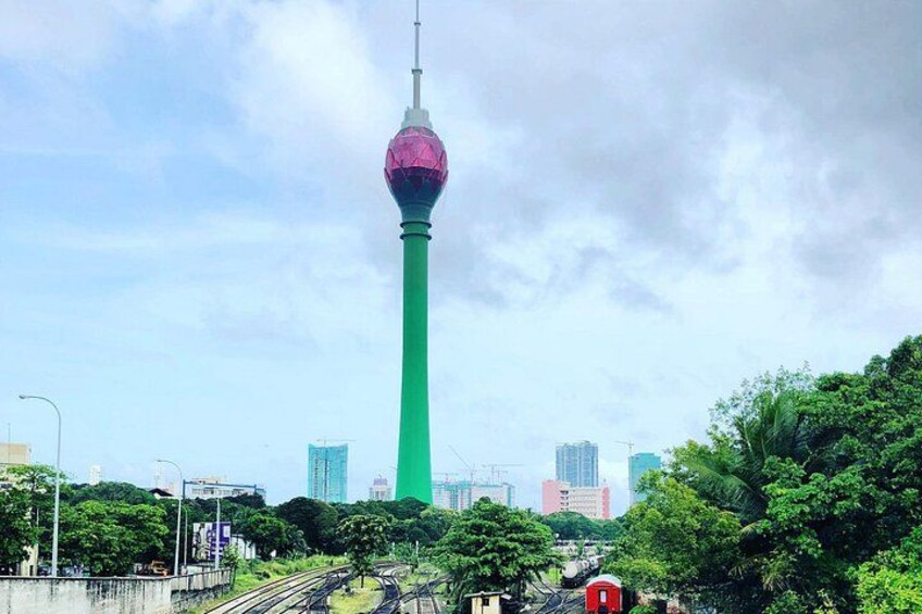 Een toren met een bolvormig uitkijkplatform, omgeven door groen en stadsgebouwen. 4
