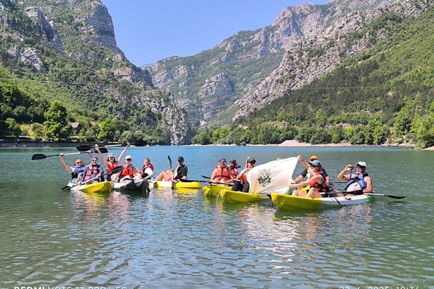 Eine Gruppe von Menschen in gelben Kanus auf einem ruhigen See vor einer Bergkulisse. 2