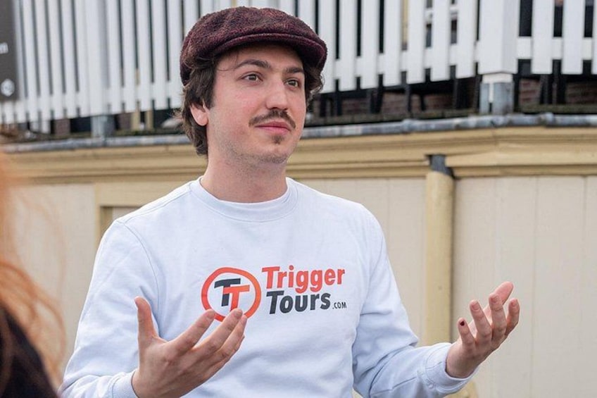 A person wearing a white long-sleeve shirt with a logo and text that reads 'Trigger Tours.' 2