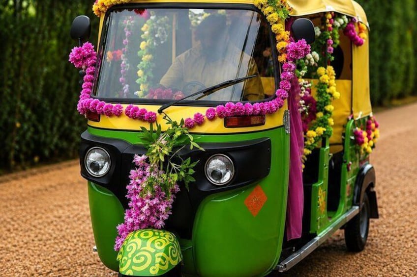 A decorated auto-rickshaw with floral garlands and a green and yellow color scheme. 2