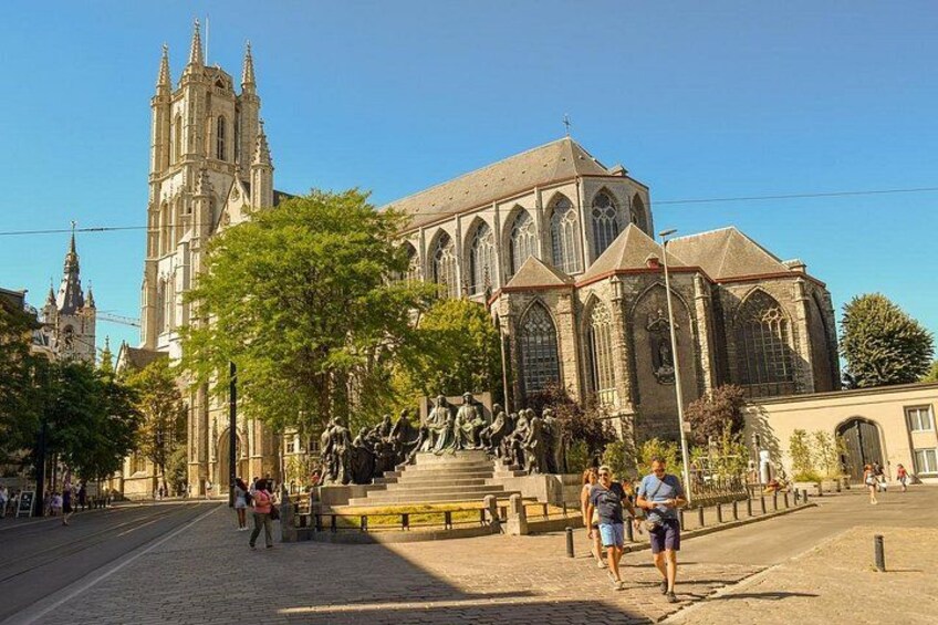 Una catedral con una estatua en primer plano, una calle empedrada y un cielo azul despejado. 2