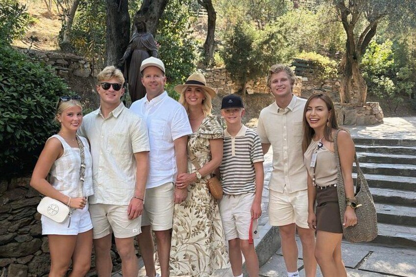 A group of people posing in a garden with stone steps and trees. 1