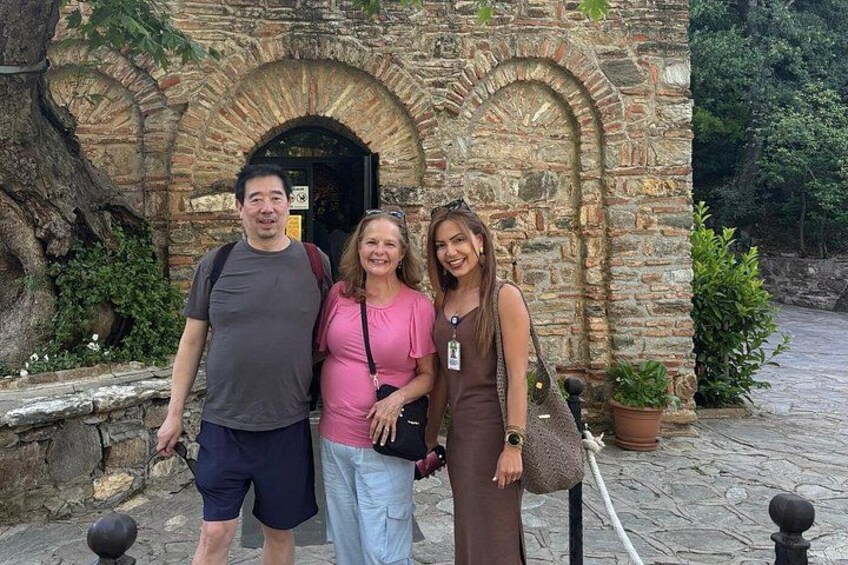 Three people standing in front of a stone building with arched doorways. 2