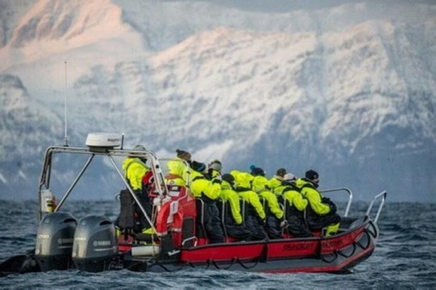 Un grupo de personas con chalecos amarillos brillantes en un bote rojo, con montañas al fondo. 2