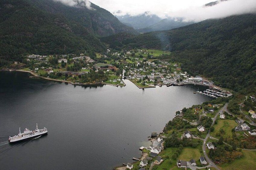 A coastal town with a large body of water, a ship, and surrounding mountainous terrain. 2