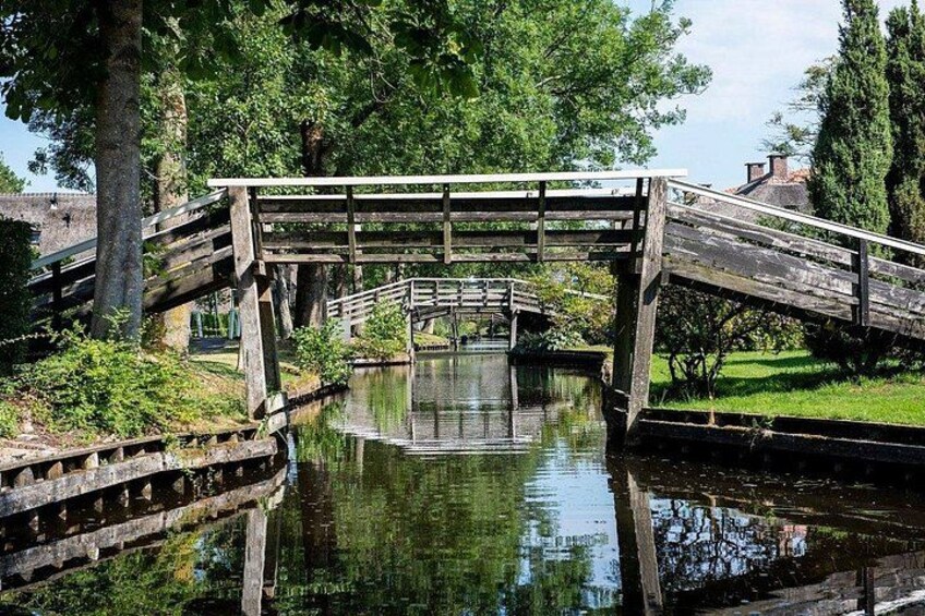 Un puente de madera sobre un canal, rodeado de árboles y hierba. 5