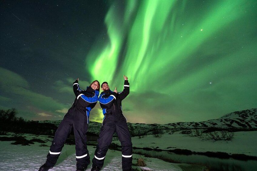 Two people posing with the Northern Lights in a snowy landscape. 5