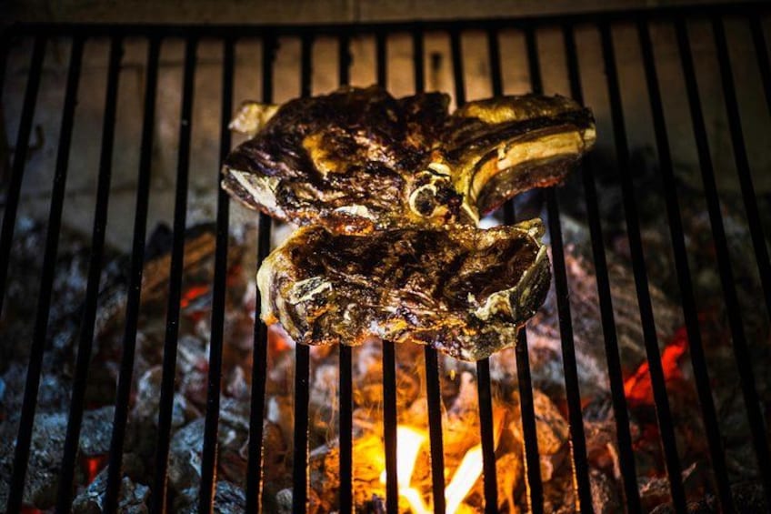 A grilled steak on a grill with visible grill marks and a fire beneath it. 4