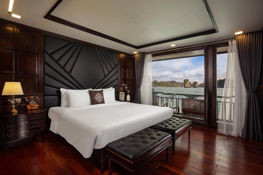 A large bed with a white bedspread, a wooden headboard, and a bench at the foot of the bed. 3