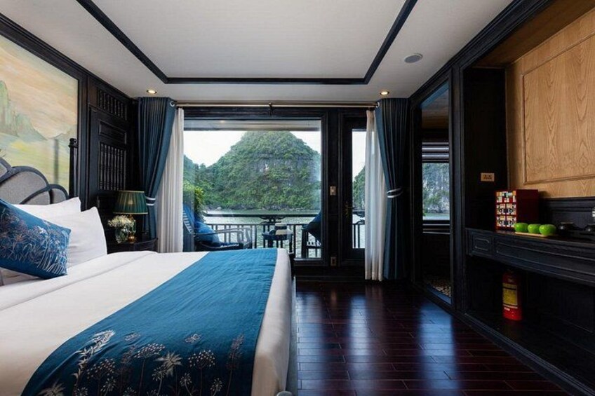 A bedroom with a large bed, a balcony with a view of a mountain, and a wooden cabinet. 4