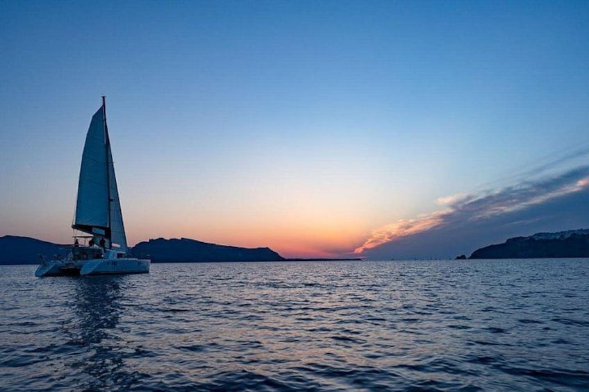 A sailboat on calm water during sunset with distant landforms. 2