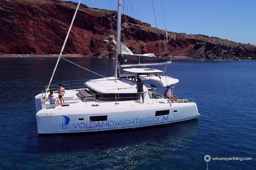 A white yacht named 'Vasiliki' on calm waters with a rocky coastline in the background. 3
