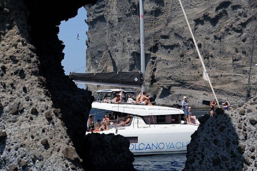 A white yacht named 'Volcano Yacht' anchored near rocky cliffs. 4