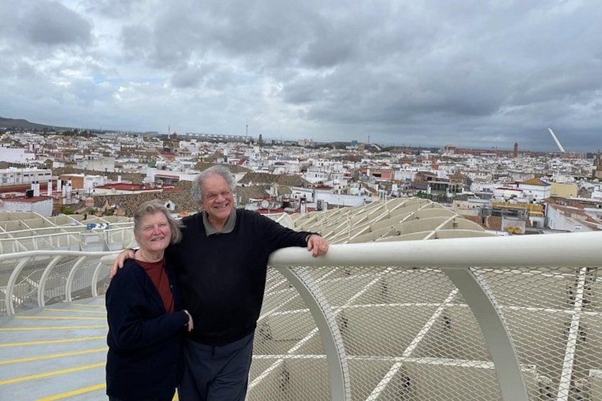 A couple standing on a bridge with a cityscape in the background. 5