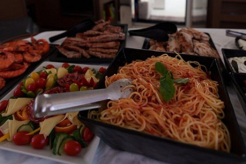 Ein Buffet mit verschiedenen Speisen, darunter Pasta, Salate und gegrilltes Fleisch. 5
