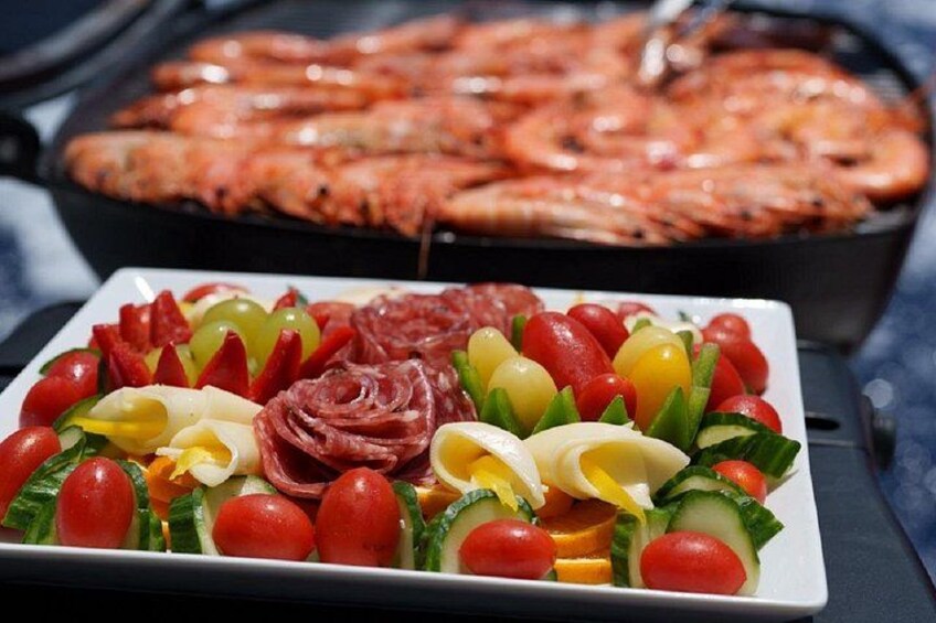 Eine Wurst- und Käseplatte mit verschiedenen Sorten sowie eine Pizza im Hintergrund. 4