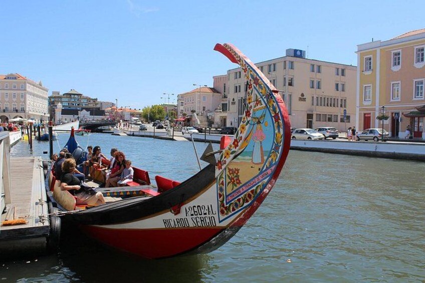 A gondola with passengers, a canal, and buildings in the background. 5