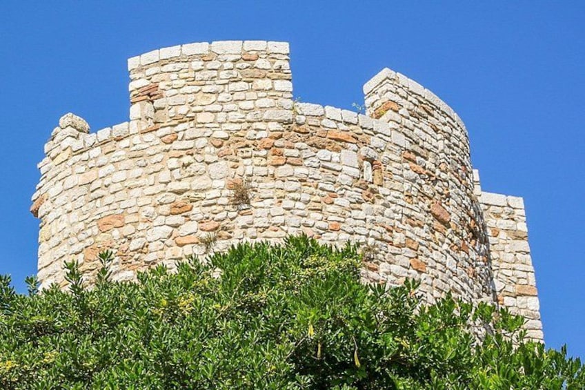 A stone tower with a circular base and a smaller top section, surrounded by greenery. 3