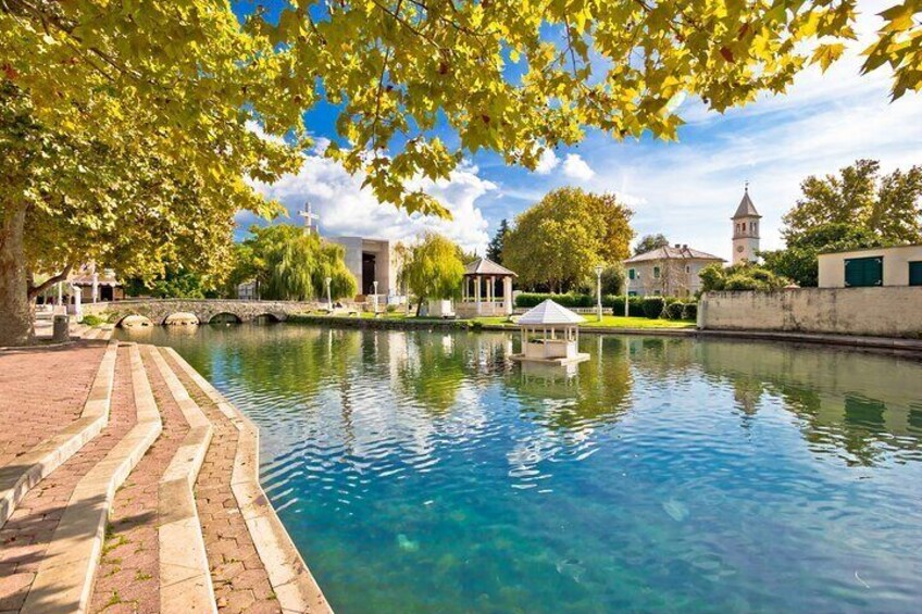 A clear blue pool with a brick pathway, a gazebo, and a church in the background. 2