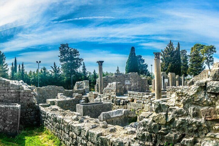 Ancient ruins with stone columns and walls, surrounded by trees and a clear sky. 5