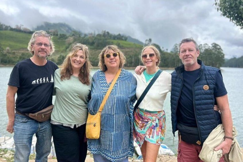 A group of people standing by a lake with a cloudy sky in the background. 1