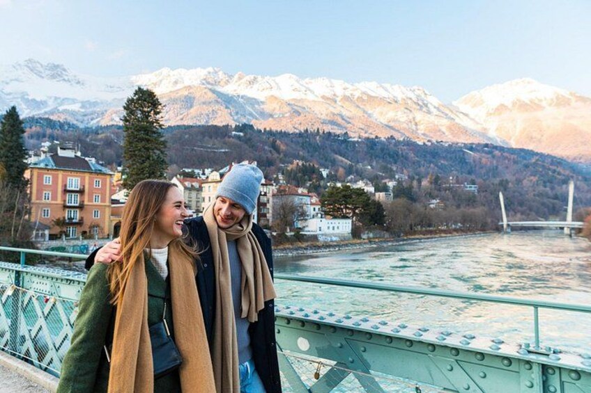 A couple on a bridge with a river and mountains in the background. 5