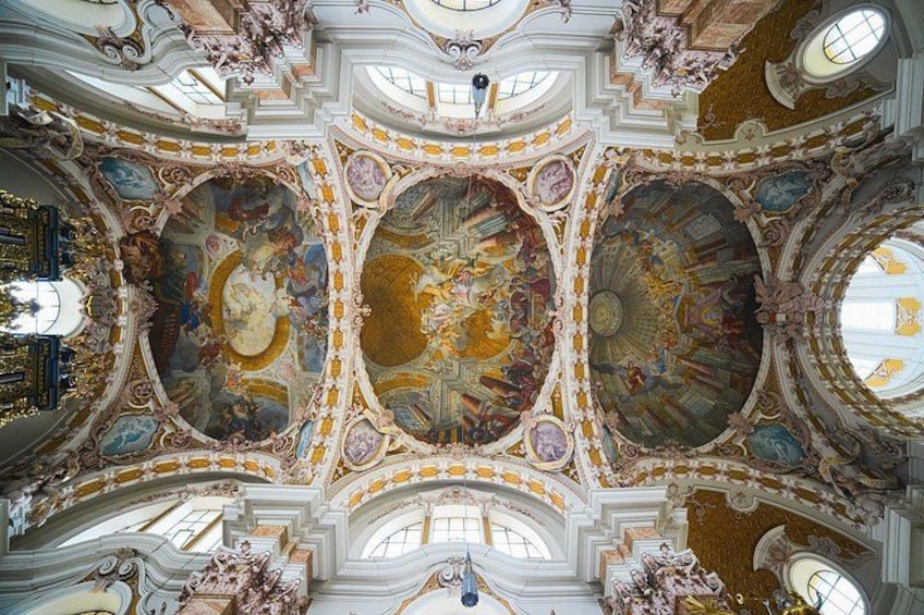 A grand hall with ornate ceilings, large windows, and intricate frescoes. 1