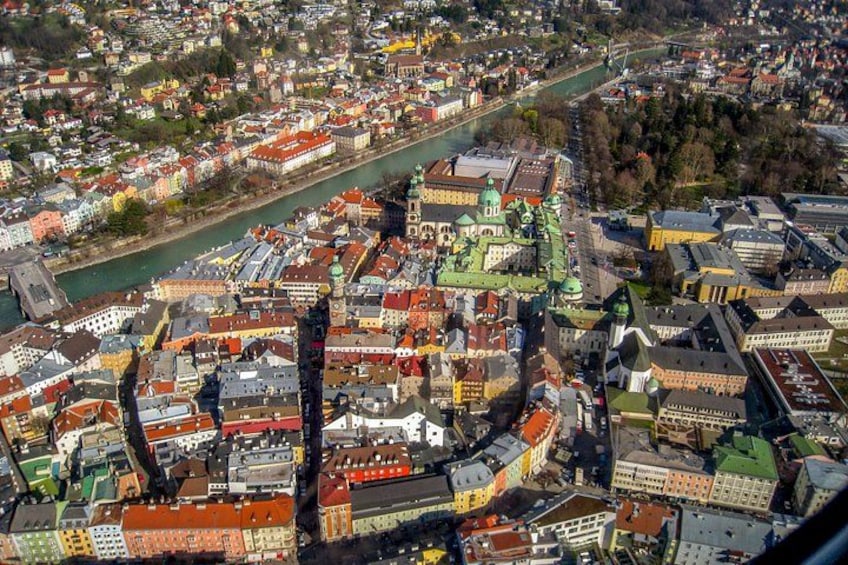 An aerial view of a city with a river, historic buildings, and a prominent green-domed church. 2